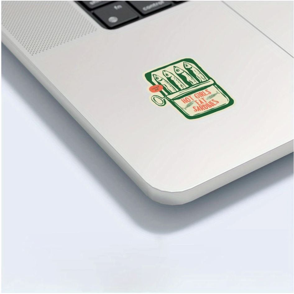 Laptop with a sticker on the palm rest area featuring cartoon-style tinned fish graphic and text.