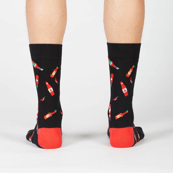 black crew socks with red heels. design has bottles of hot sauce and chili peppers all over