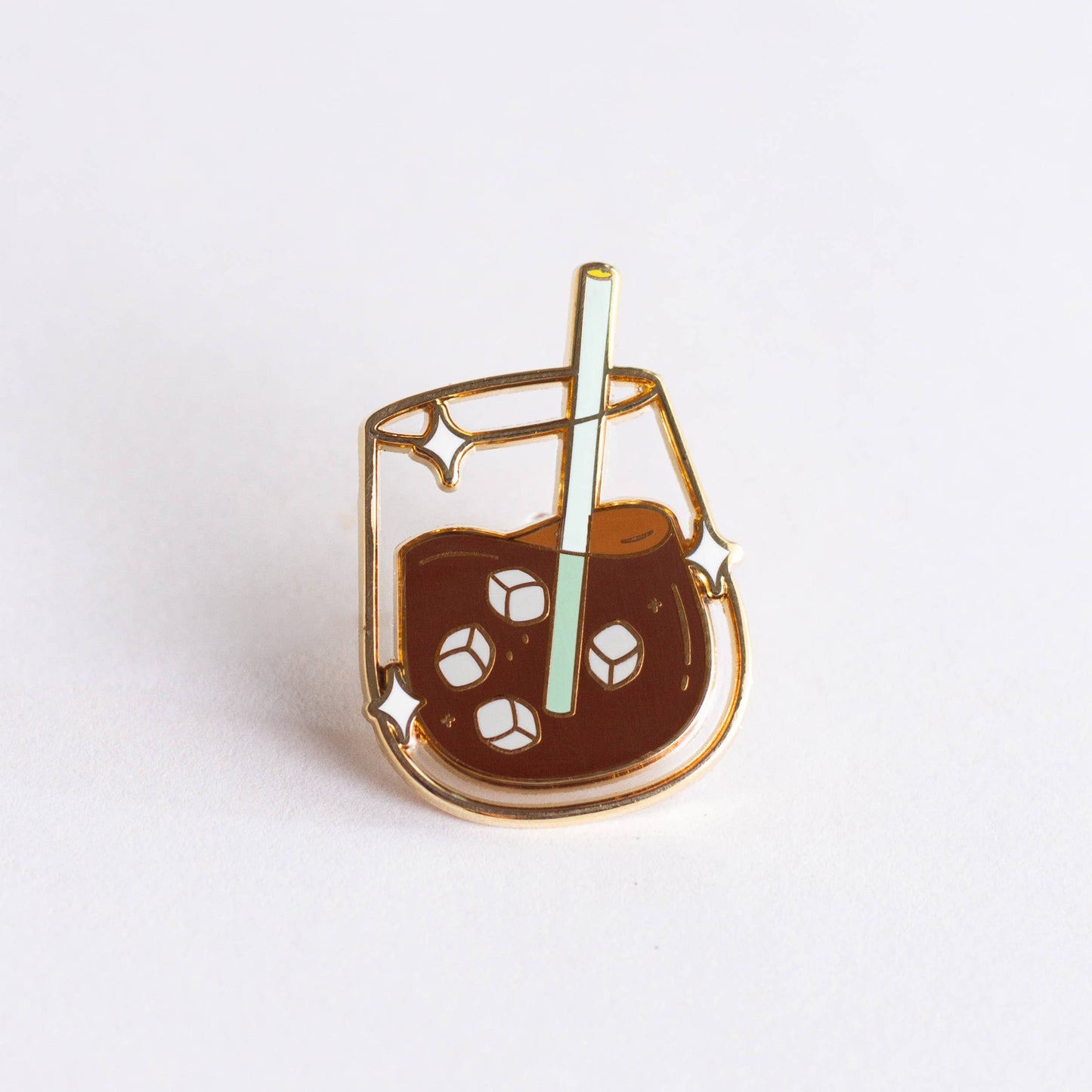 Enamel pin of a glass of iced coffee with a straw on a white background