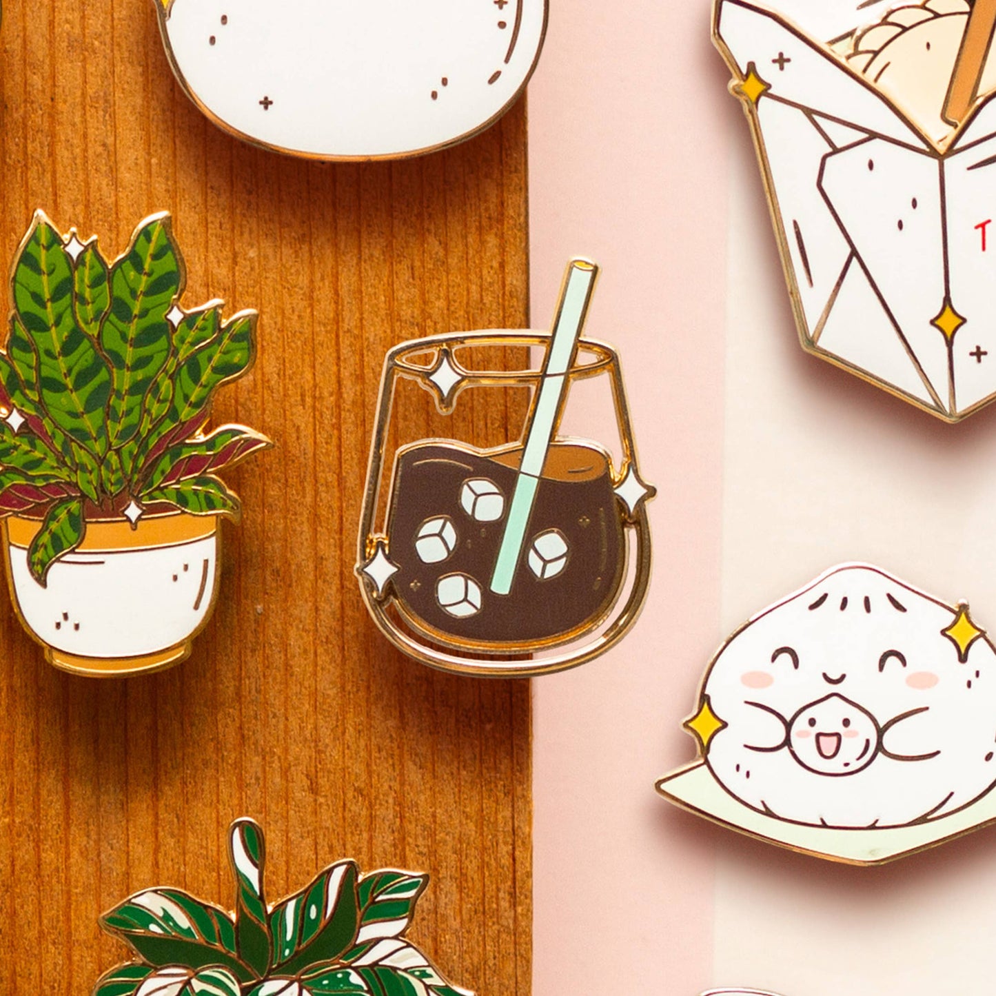 Collection of cute enamel pins on a wooden and pink background