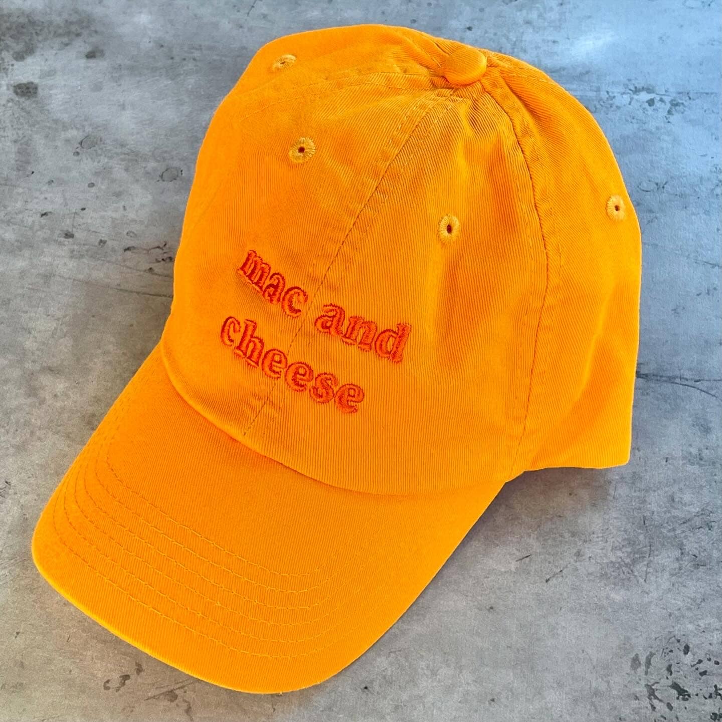 Orange hat with orange embroidery that reads: mac and cheese