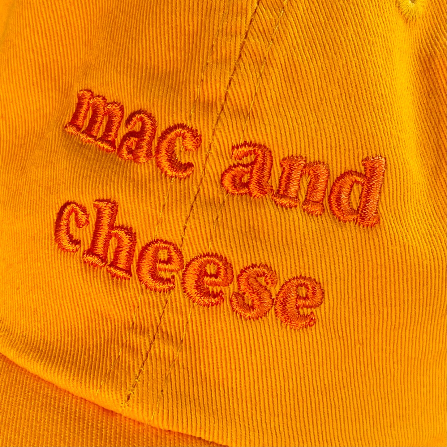 Orange hat with orange embroidery that reads: mac and cheese