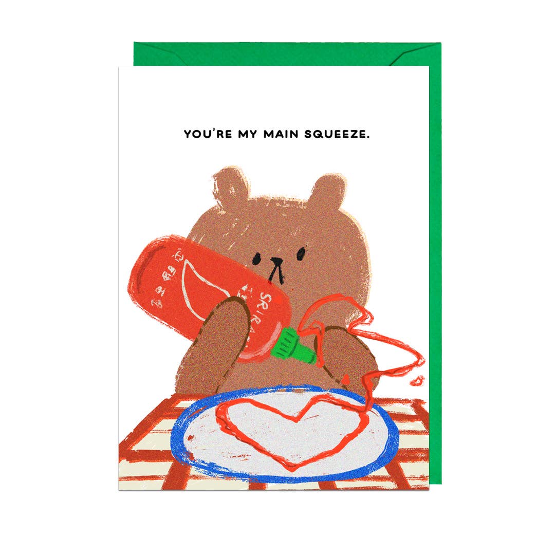 greeting card with a bear at a table, squeezing a bottle of sriracha and making a heart on a plate. Text reads "You're my main squeeze"