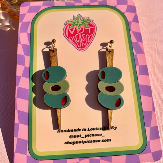 Pair of olive pick earrings on a colorful card with 'Not Picasso' branding.
