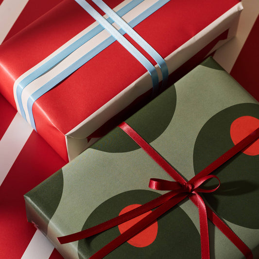 Two gift boxes, one red and white stripes with blue ribbon and one with green olive design with red ribbon, on a red and white striped background.