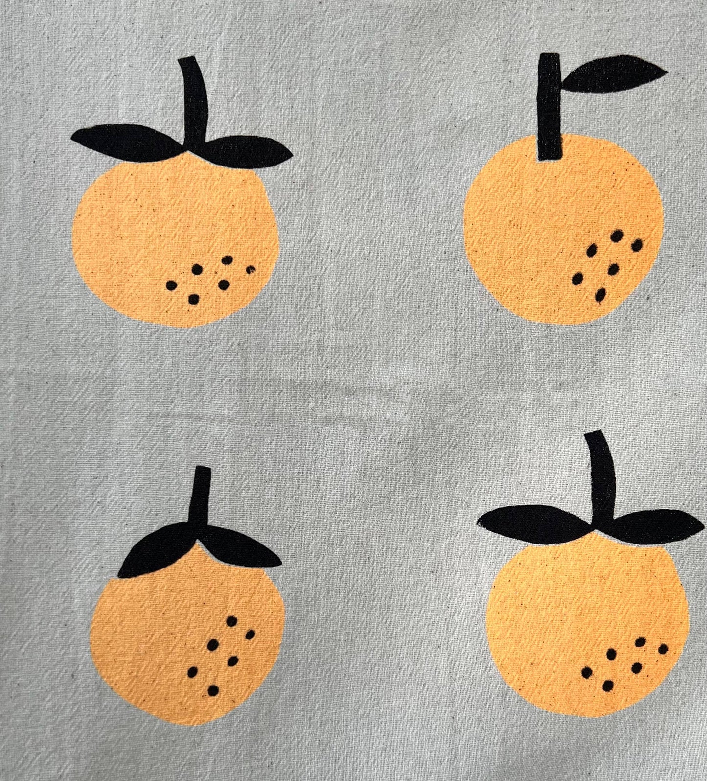 Linen tea towel with oranges screen printed on it. Close up view