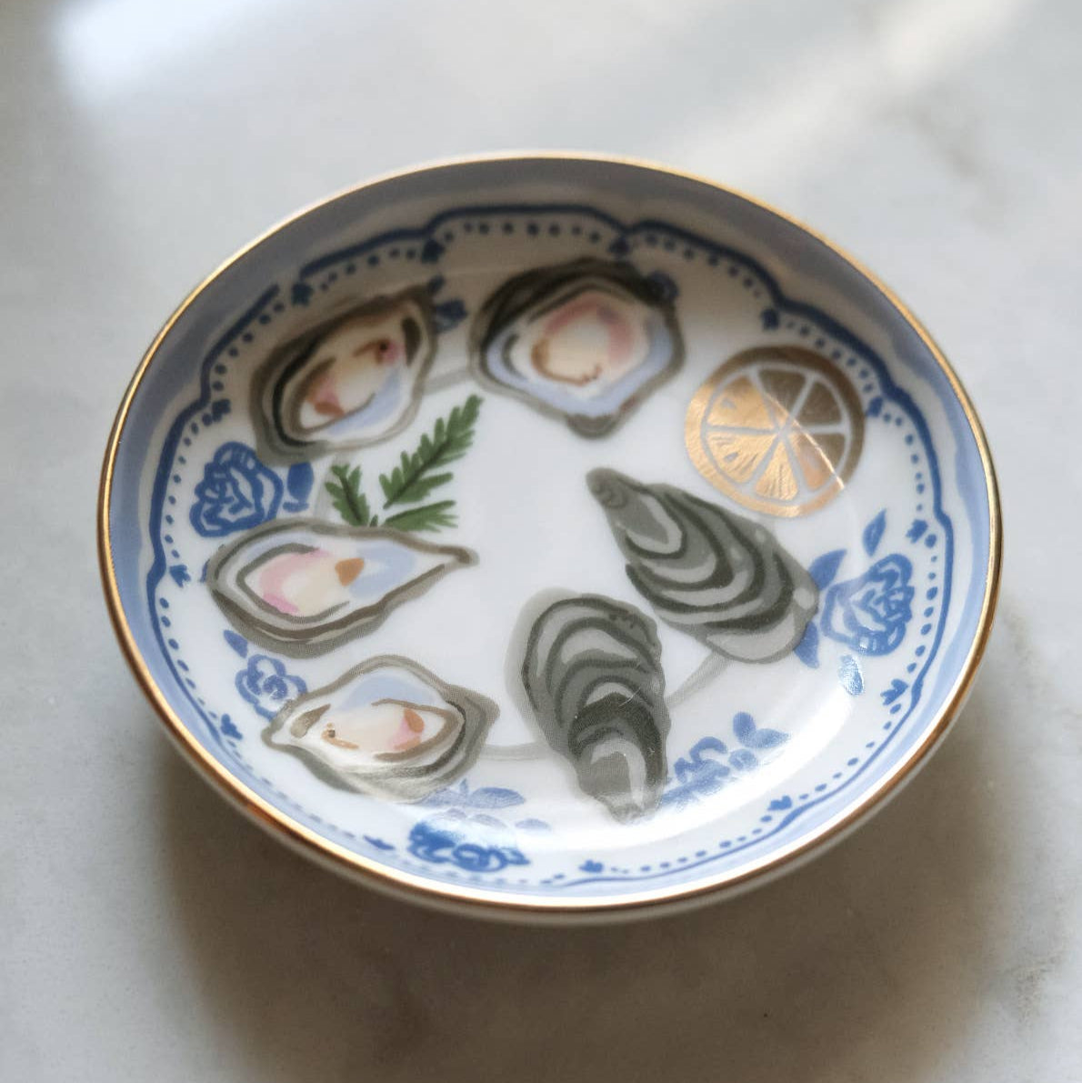Decorative plate with illustrations of oysters and lemon on a marble surface