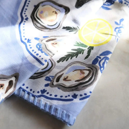 Folded fabric with oyster and lemon design on a neutral background