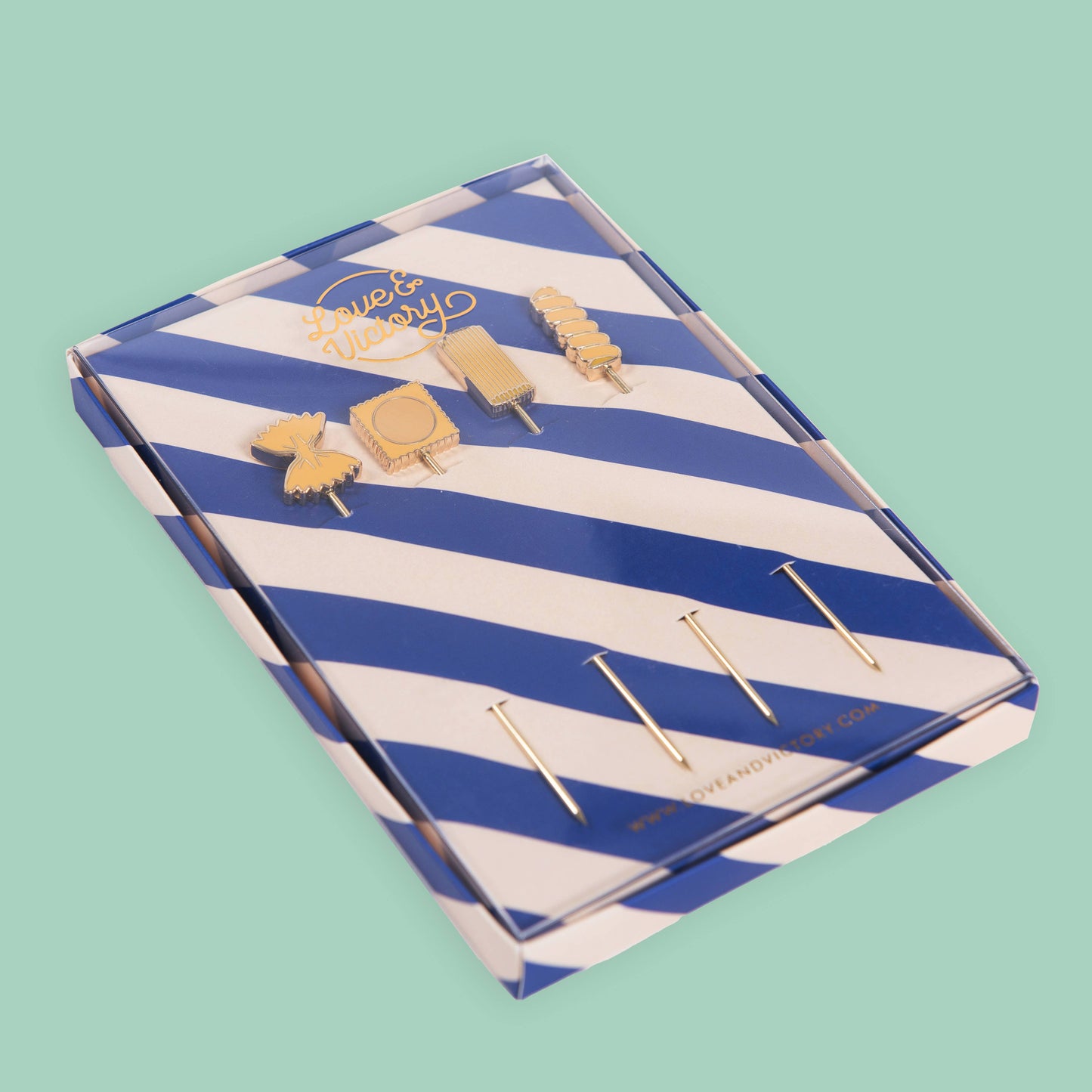 Pasta themed cocktail picks in a blue and white striped box on a light green background