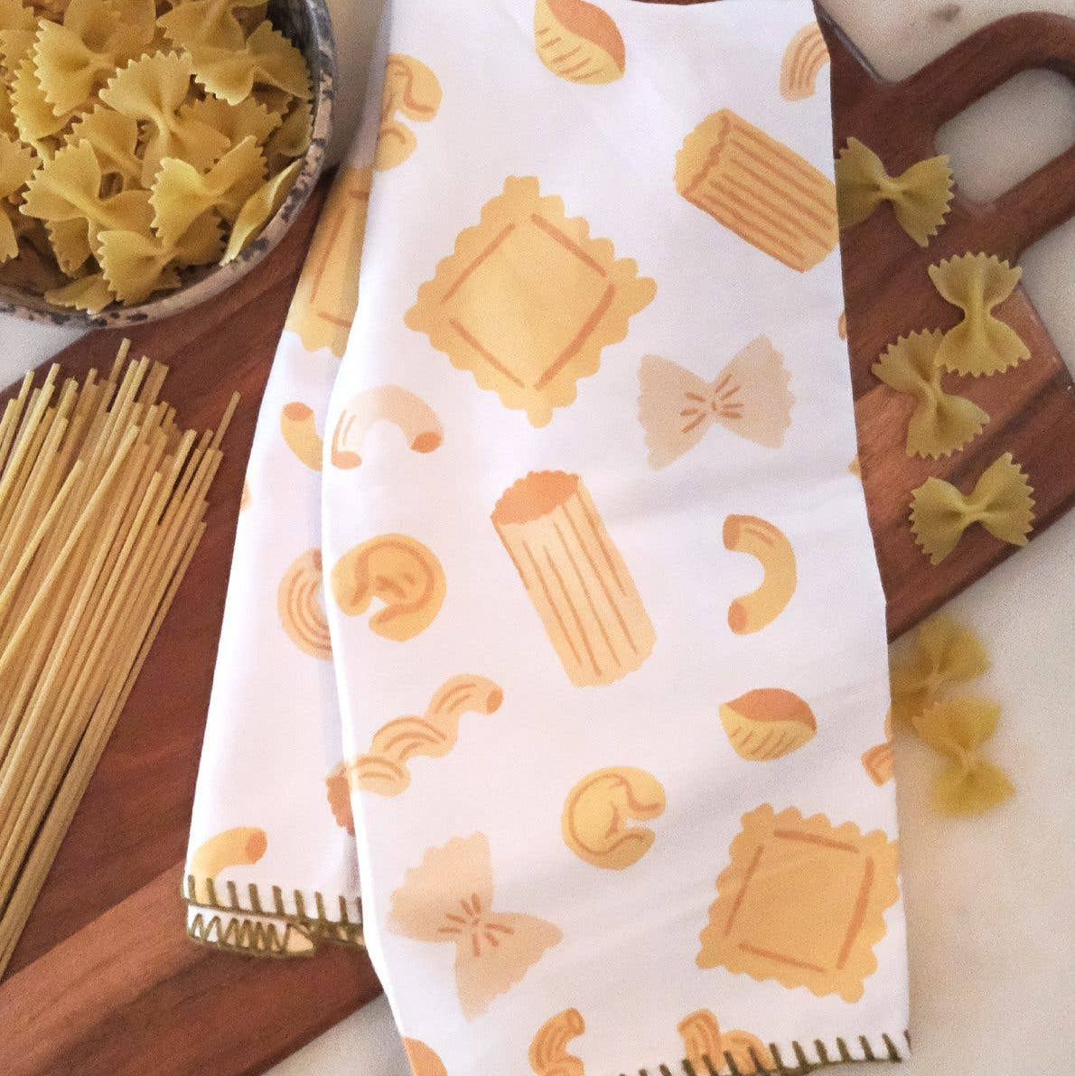 Kitchen towel with pasta pattern on a table with pasta ingredients