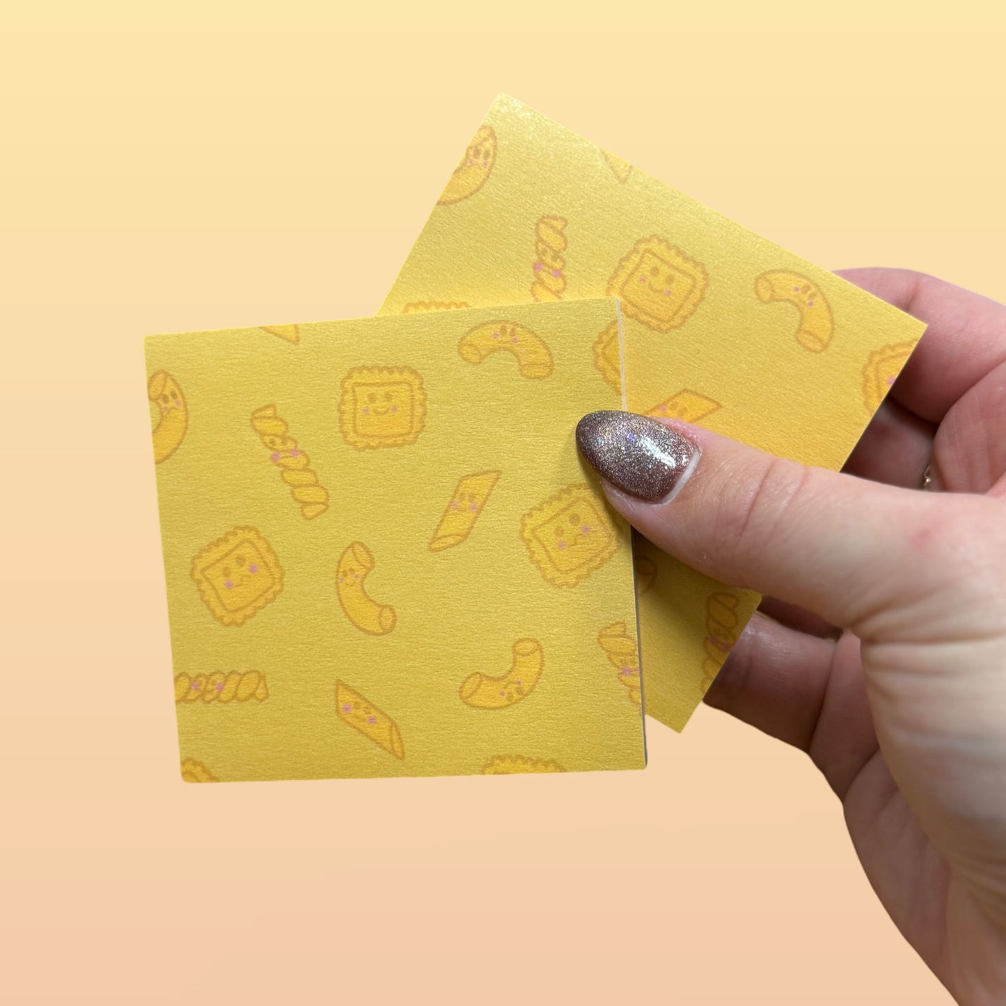 Hand holding two yellow sticky notes with a pasta pattern on a yellow background