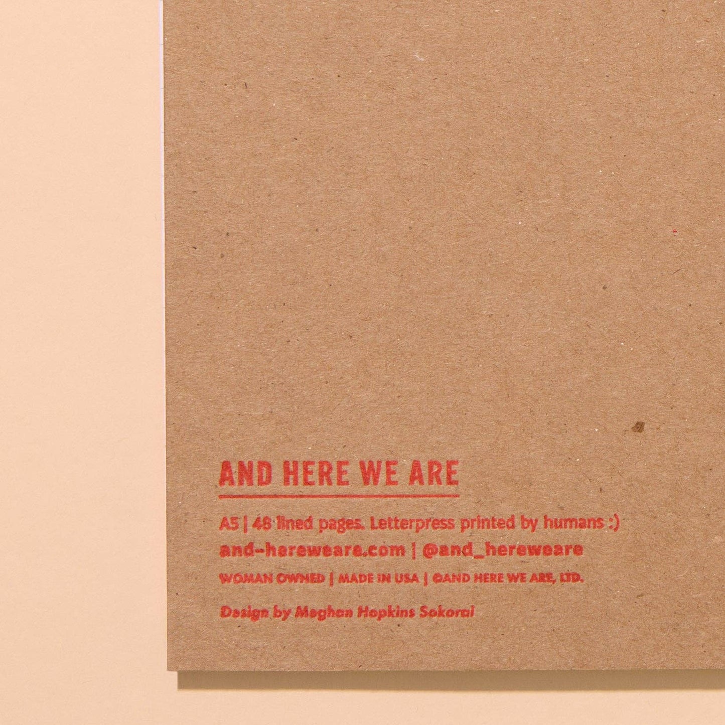 close up image of back, bottom left corner of pickle notebook. Red text that has brand name along with details of notebook manufacturing