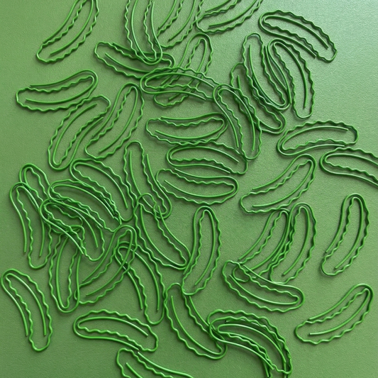 Green pickle shaped paper clips on a green background