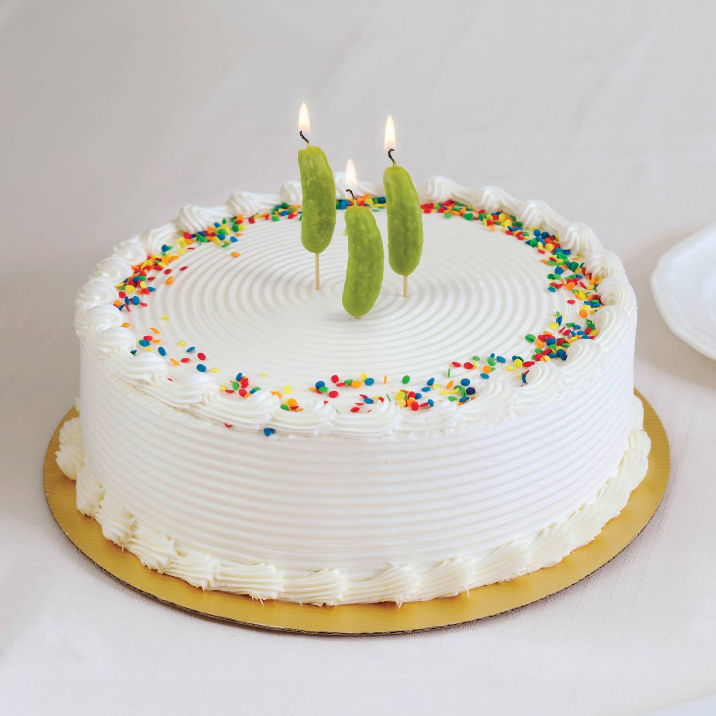 three, pickle shaped birthday candles on a cake, all lit