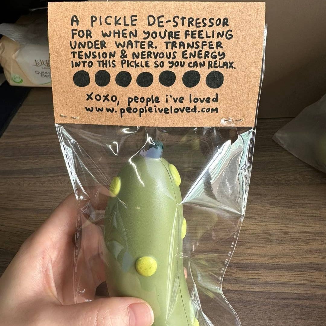 pickle stress ball with text that reads "hold me in a pickle" in plastic packaging showing the back