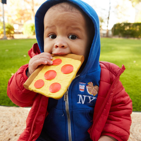 Child holding a toy pizza slice outdoors