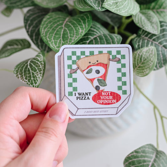 Hand holding a sticker with a cartoon character and text, against a leafy green background