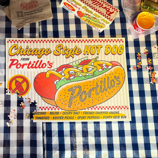 Table with food and a Portillo's hot dog sign on a checkered tablecloth