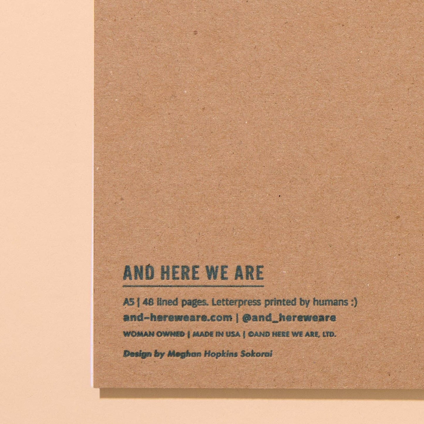 Brown cardboard backing with text about 'And Here We Are' brand on a beige background