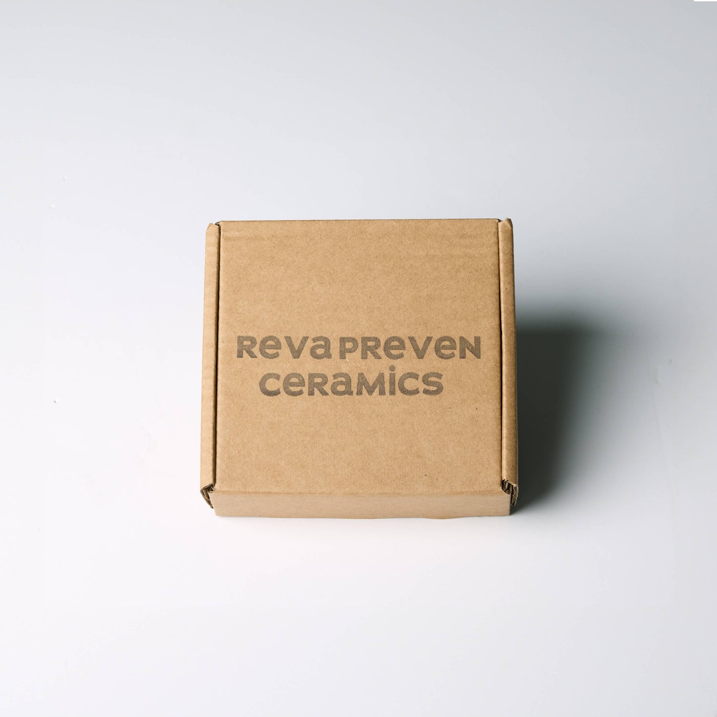 Brown cardboard box with 'RevaPreven Ceramics' branding on a white background