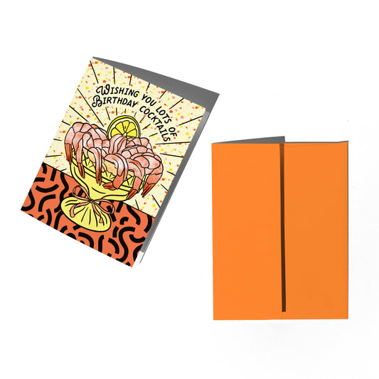 Colorful birthday card with shrimp cocktail illustration and orange envelope on a white background