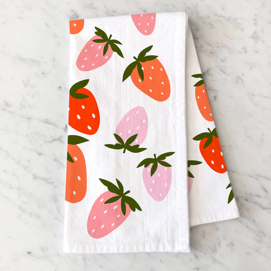 Folded, white kitchen towel with pink and red strawberries on it