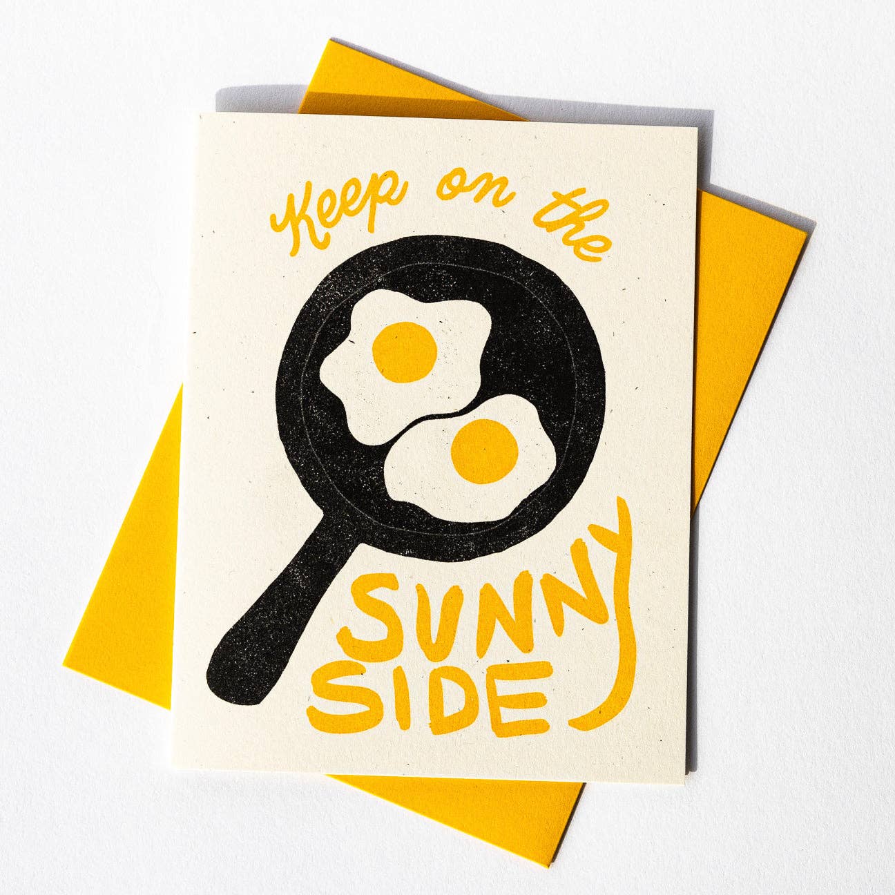 Greeting card with two sunny side up eggs in skillet with text that reads "Keep on the sunny side"
