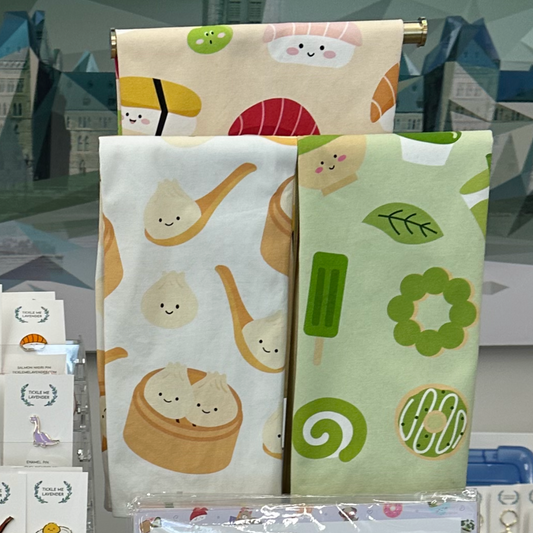 3 kitchen towels, bao, matcha sushi, on display table with other items