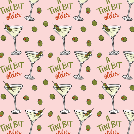 Pattern of martini glasses with olives and text 'A TINI BIT older' on a pink background.