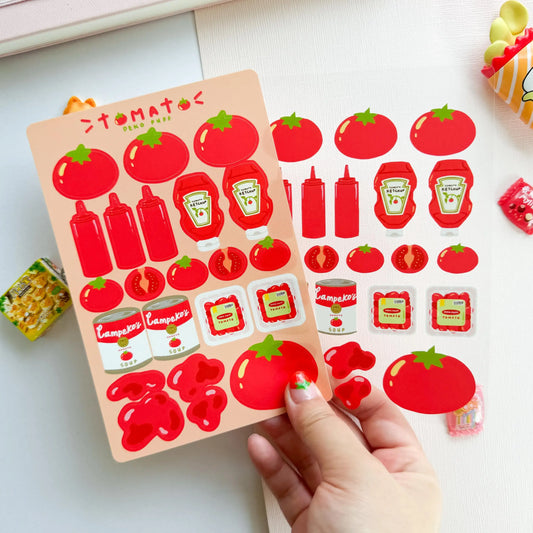 Sticker sheet with tomato and ketchup designs held by a hand on a white background