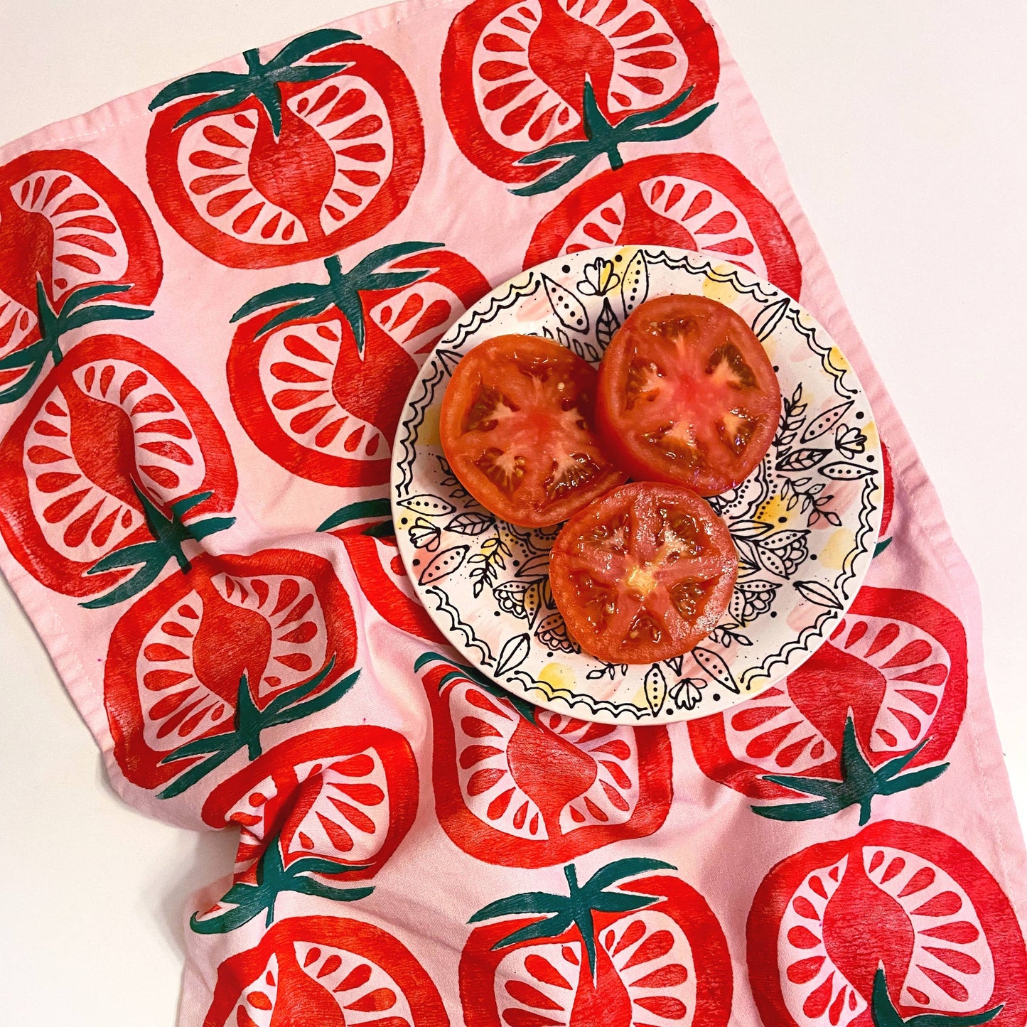 pink kitchen towel with repeated pattern of a half-cut tomato