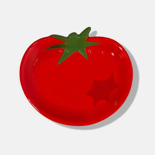 Red tomato-shaped plate with a green stem on a white background