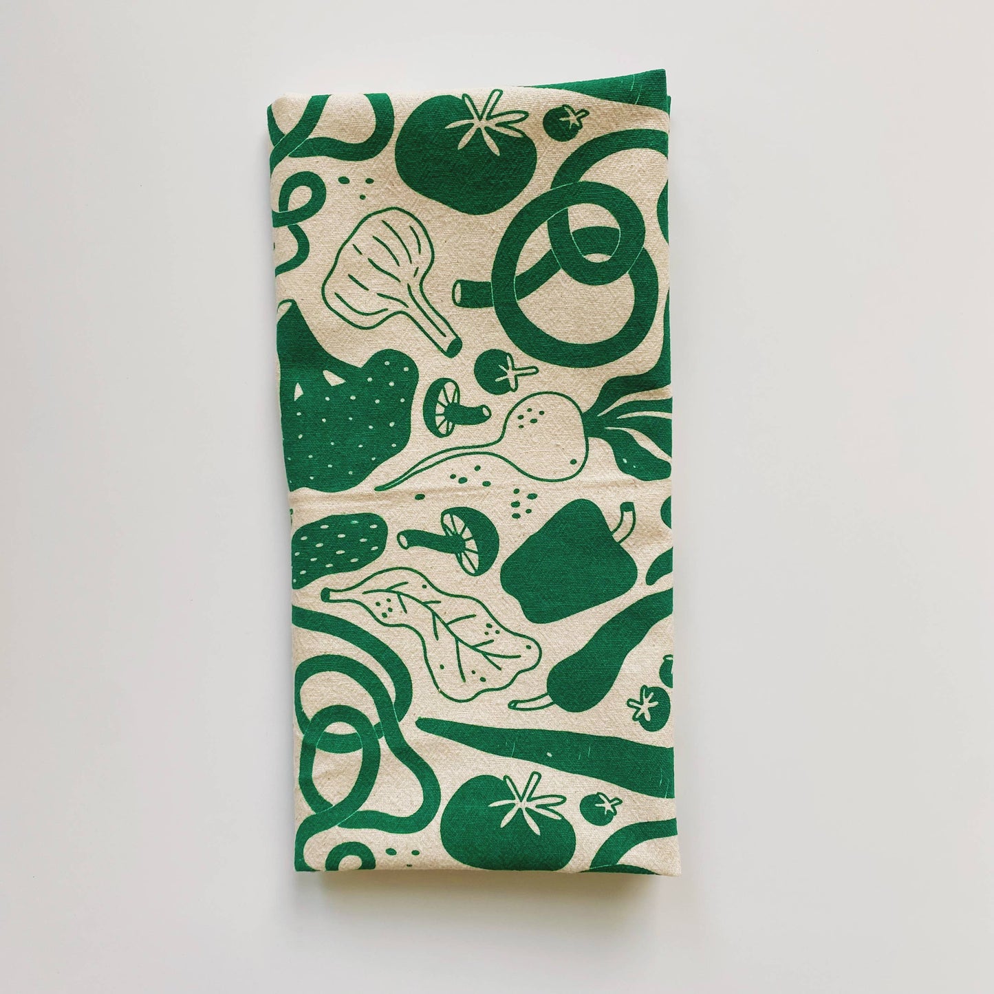 Kitchen towel with various veggies on it including, tomatoes, garlic, mushrooms, bell pepper, beets. Printed with green ink on natural colored towel