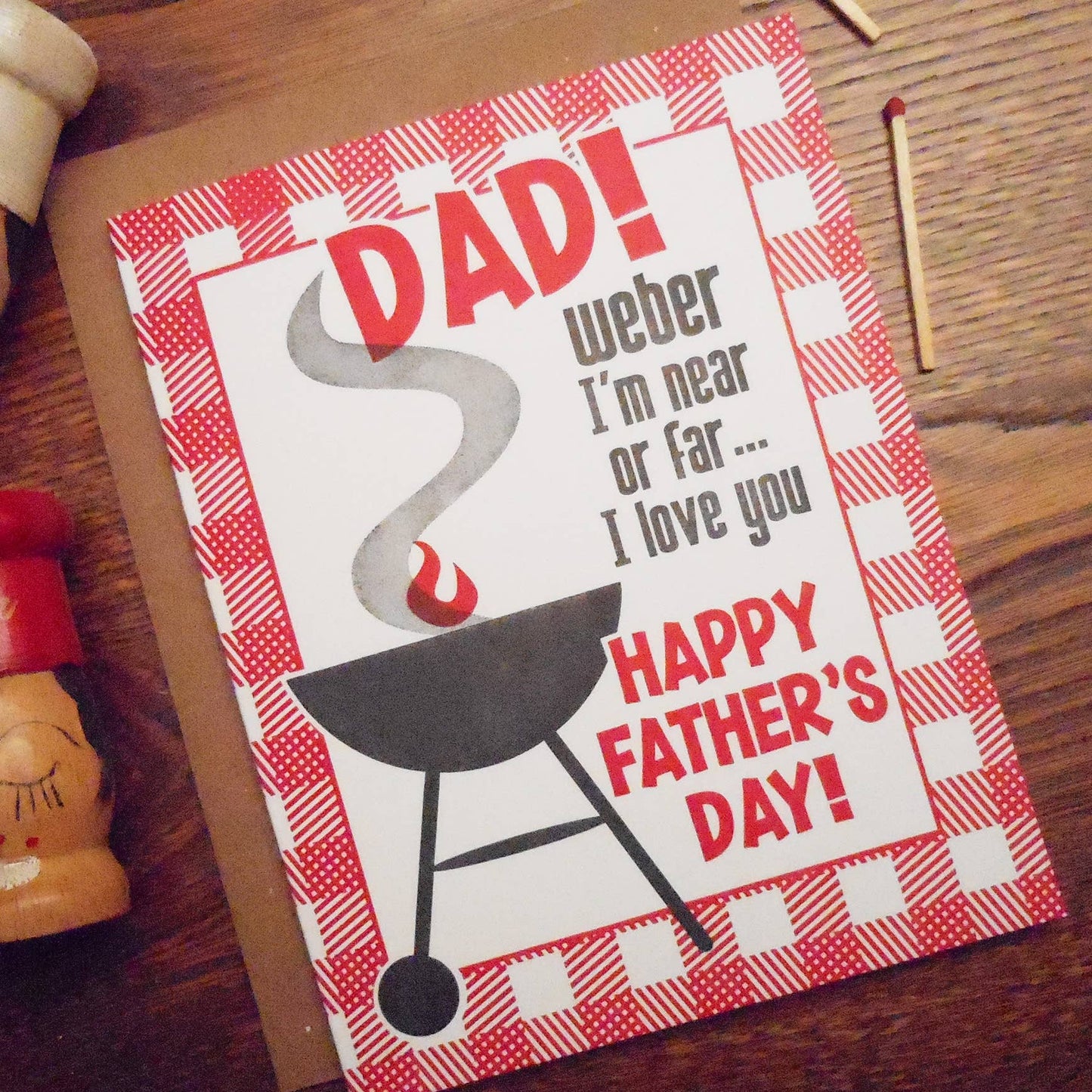 Father's Day card with BBQ design and text on a wooden surface
