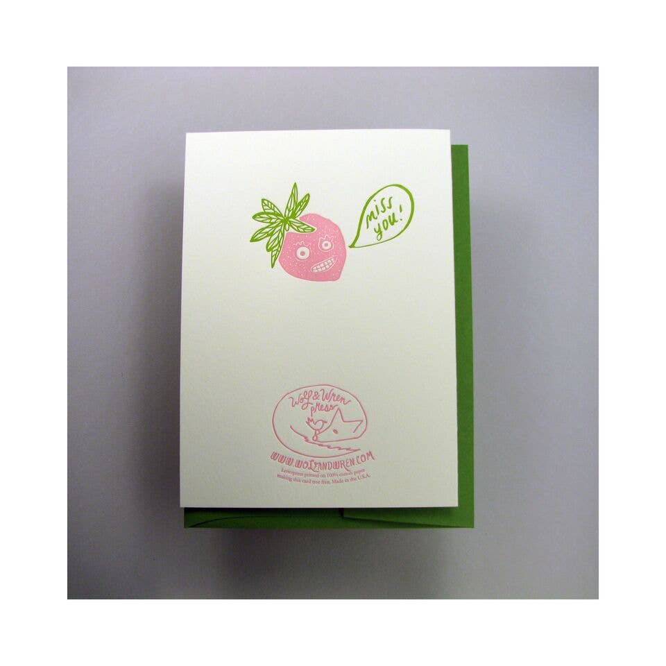 Back of weird strawberry bunch card -- has illustration of a strawberry with a silly face and a thought bubble that reads "miss you!"