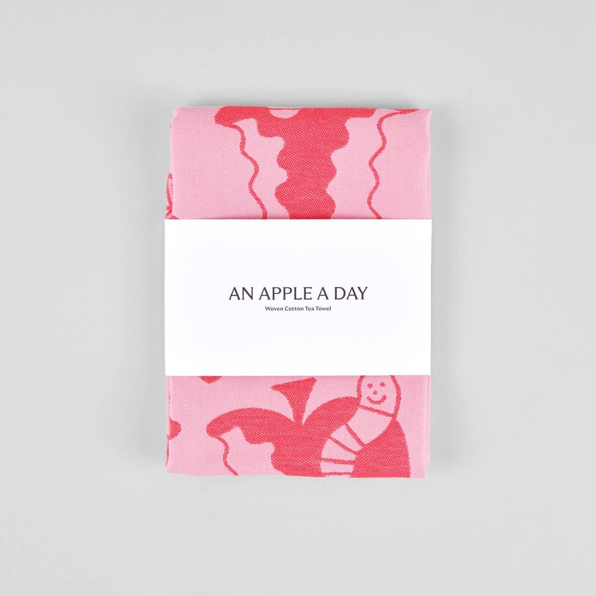 "An Apple A Day" red and pink kitchen towel wrapped in a paper band packaging