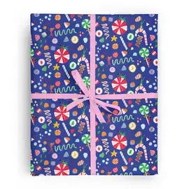 Box wrapped in blue wrapping paper that features a variety of candies and tiny people tumbling around in santa hats. Tied with a pink ribbon.