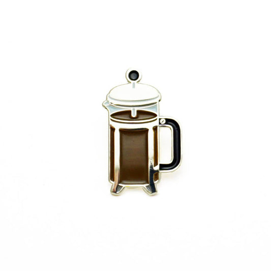 Enamel pin shaped like a glass French press full of coffee.