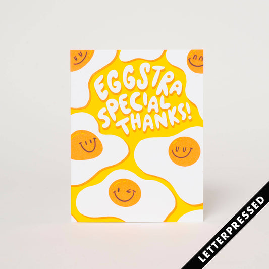Letterpress printed greeting card with image of smiling fried eggs on bright yellow background and text "Eggstra Special Thanks!"