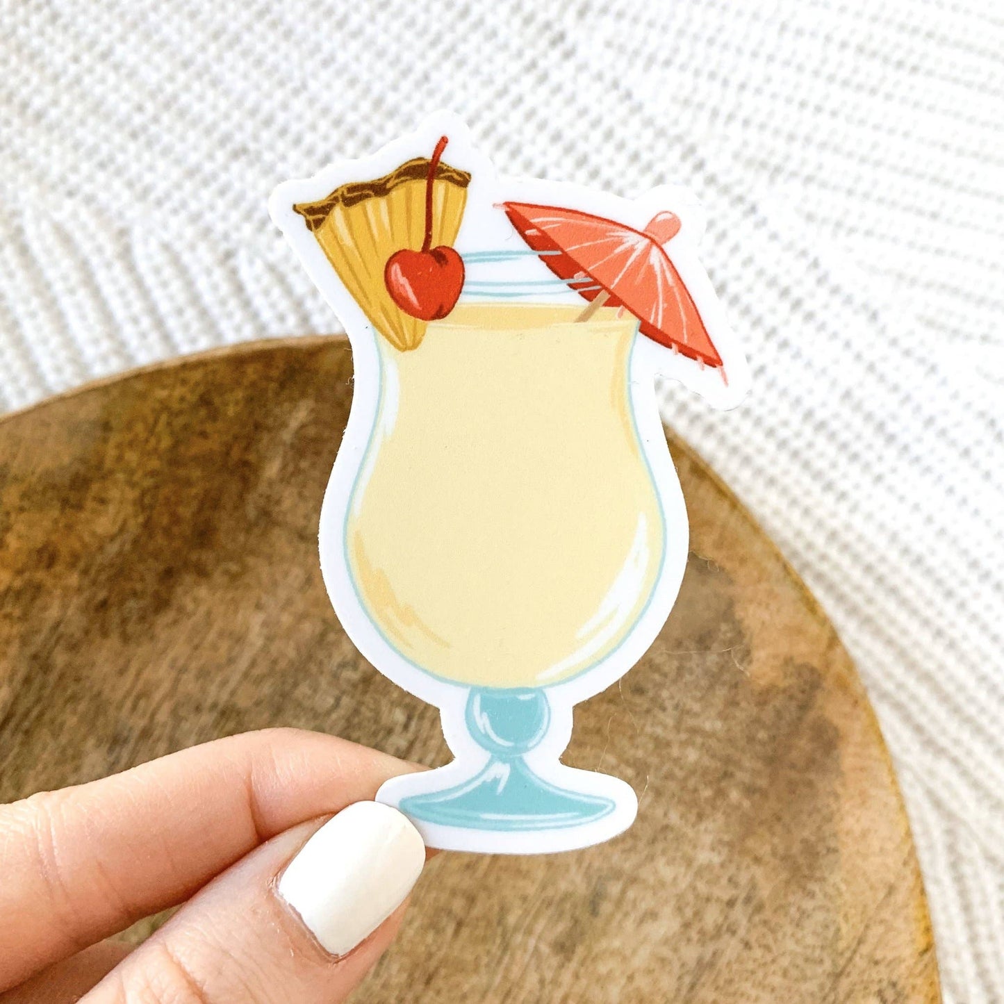 Sticker of a pina colada accompanied with a umbrella pick, pineapple slice and maraschino cherry