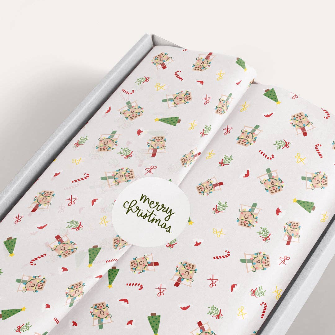 Holiday tissue paper with candy canes, a smiley boba cup dressed in christmas lights, christmas tree, mistletoe and red birds all over