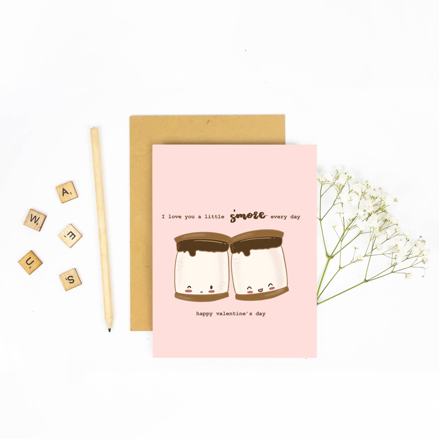 Valentine's Day card that says "I love you a little s'more every day... happy valentine's day" with illustration of two pudgy s'mores with cute smiling faces on pale pink background.