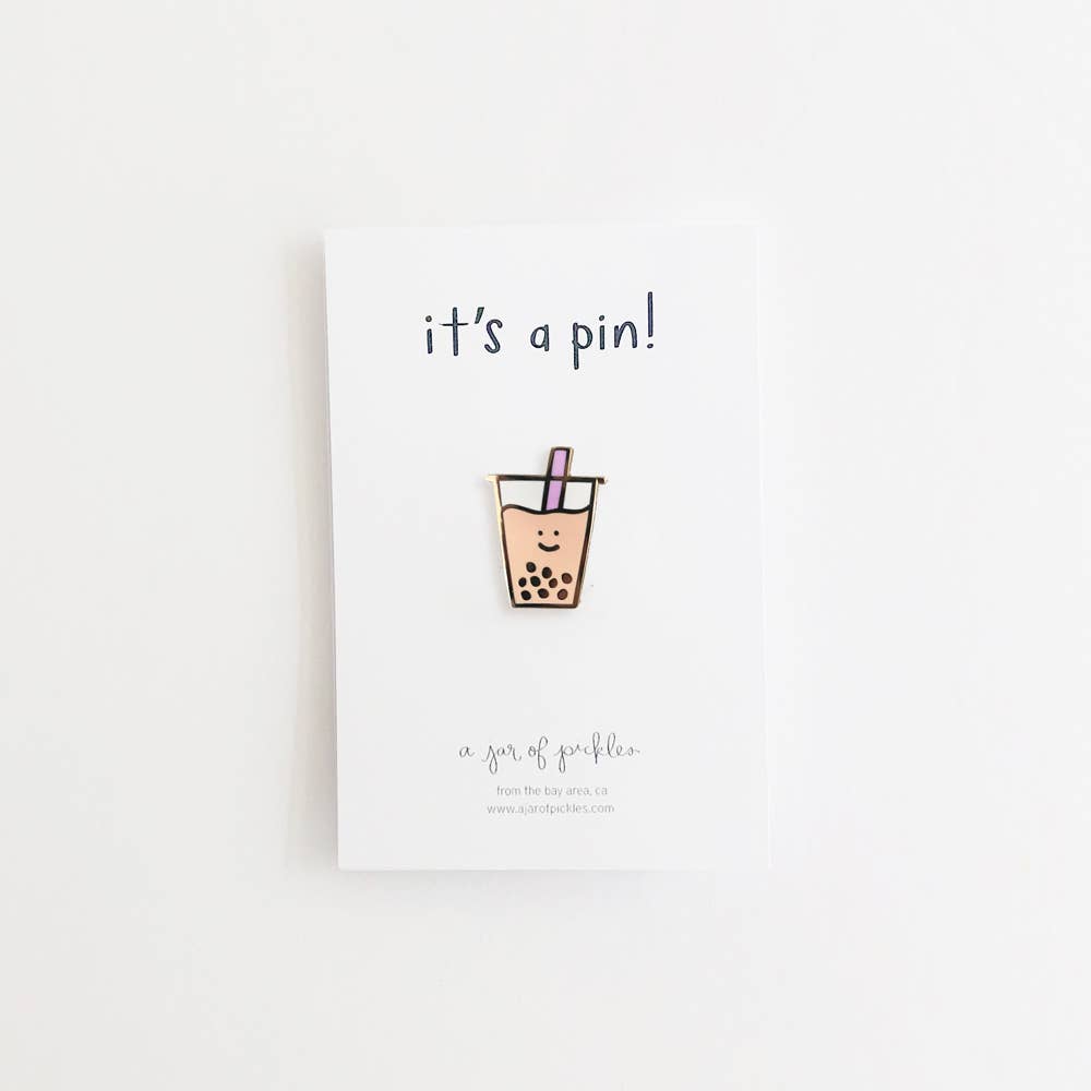 Boba cup enamel pin with a smiley face, placed on white card backing that says "it's a pin!"