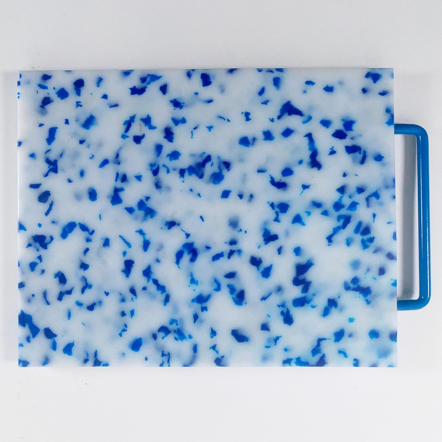 mostly white cutting board with blue confetti throughout, handle is blue