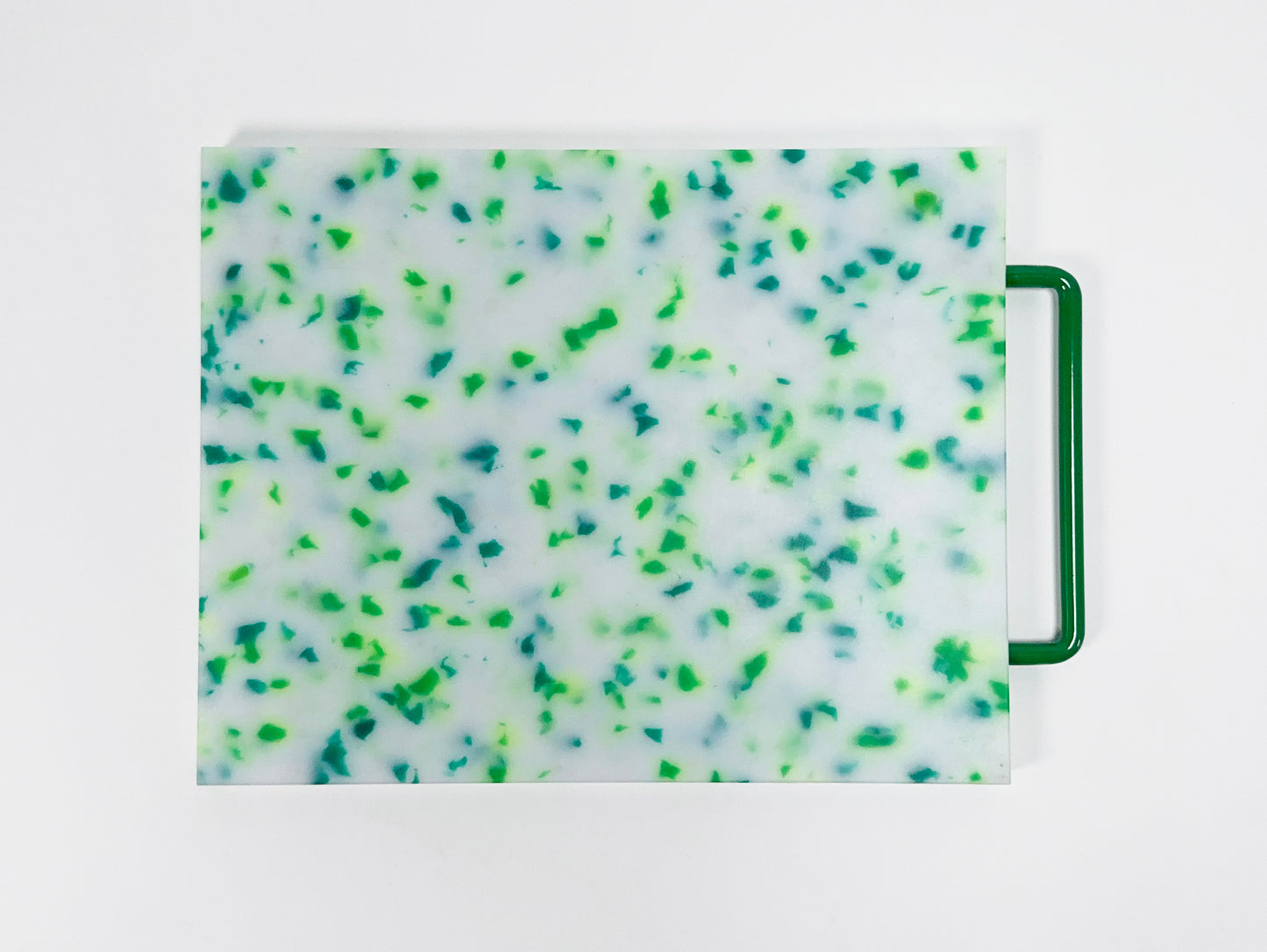 mostly white cutting board with blue and green confetti throughout, handle is green