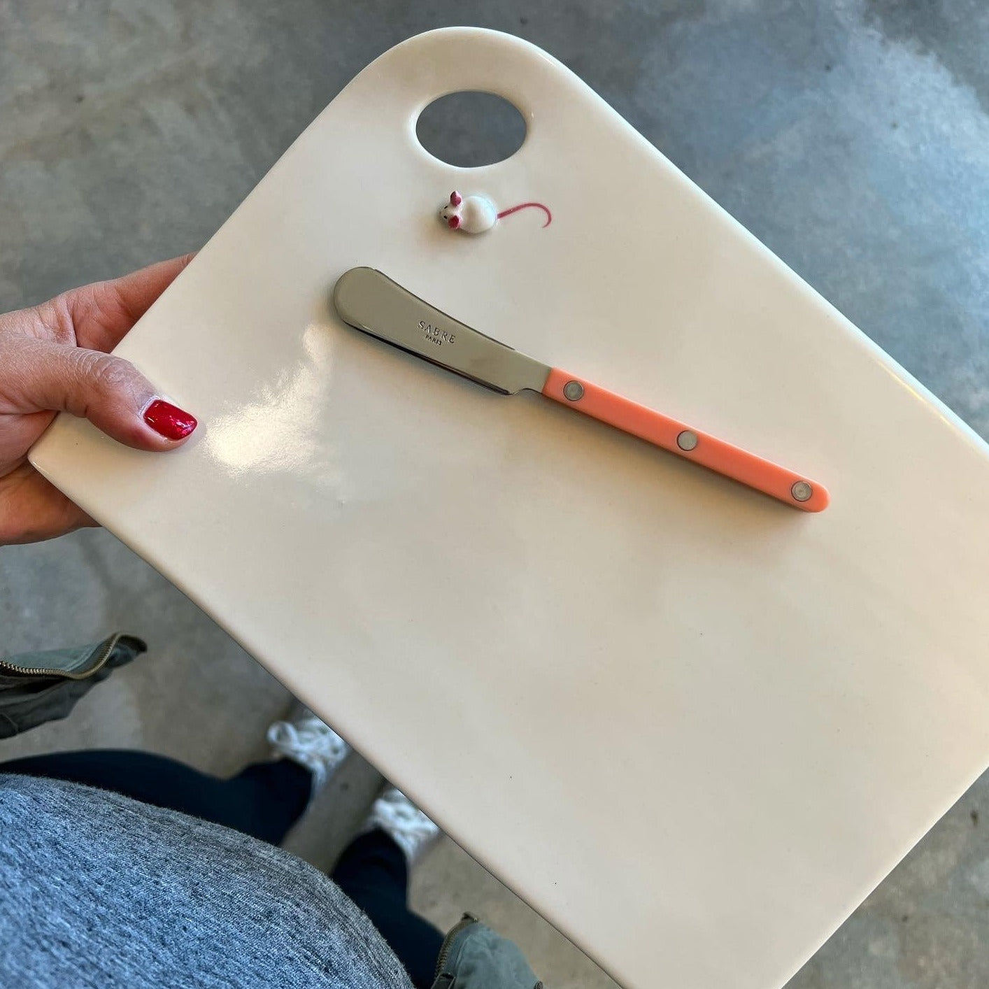 White, rectangular cheese plate with a loop and small mouse in the top left corner. Pink sabre on top of the plate.
