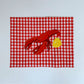 Red gingham placemat with a red lobster and lemon half embroidered in the middle 
