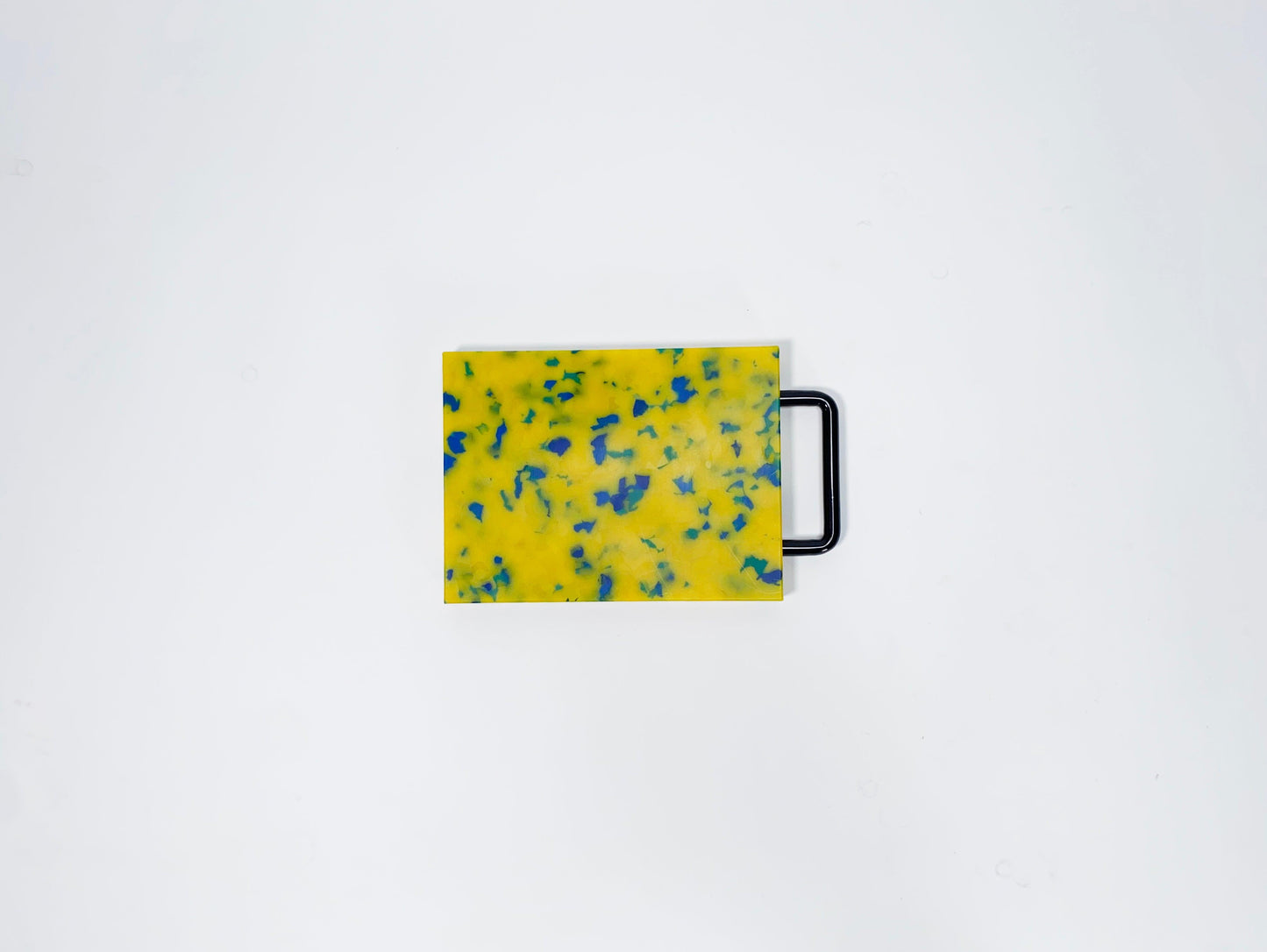 Small yellow cutting board with blue confetti and black handle