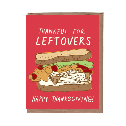 Greeting card with text "Thankful for leftovers...Happy Thanksgiving!" and illustration of a large over-stuffed sandwich made from Thanksgiving leftovers on a bright pink background.
