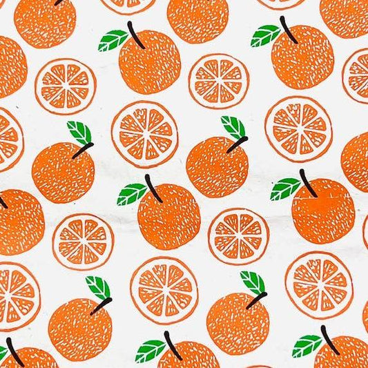 Single sheet of gift wrap with whole and cut oranges as the design